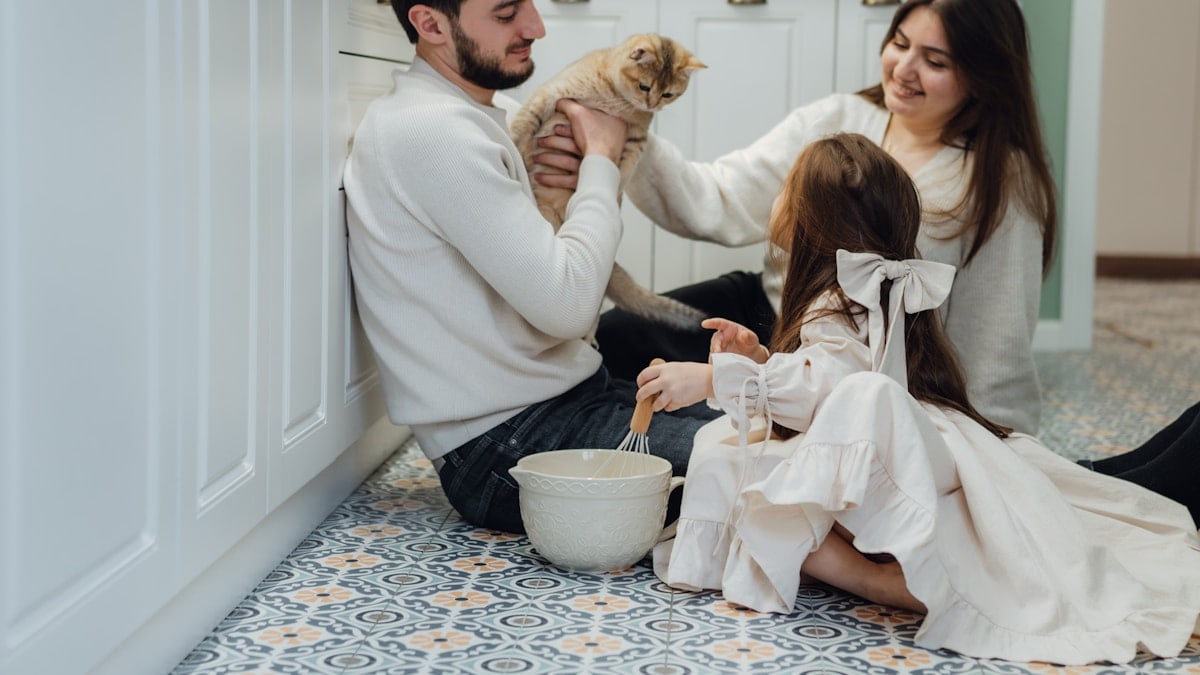 A man and a woman sitting on the floor with a dog